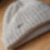 A close-up of a stylish white beanie on a wooden surface, showcasing its texture and design.